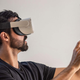 2021 a vu une augmentation de 31 % des réclamations d'assurance liées à la réalité virtuelle 1 Un homme est assis dans sa chambre tout en utilisant un casque VR blanc.